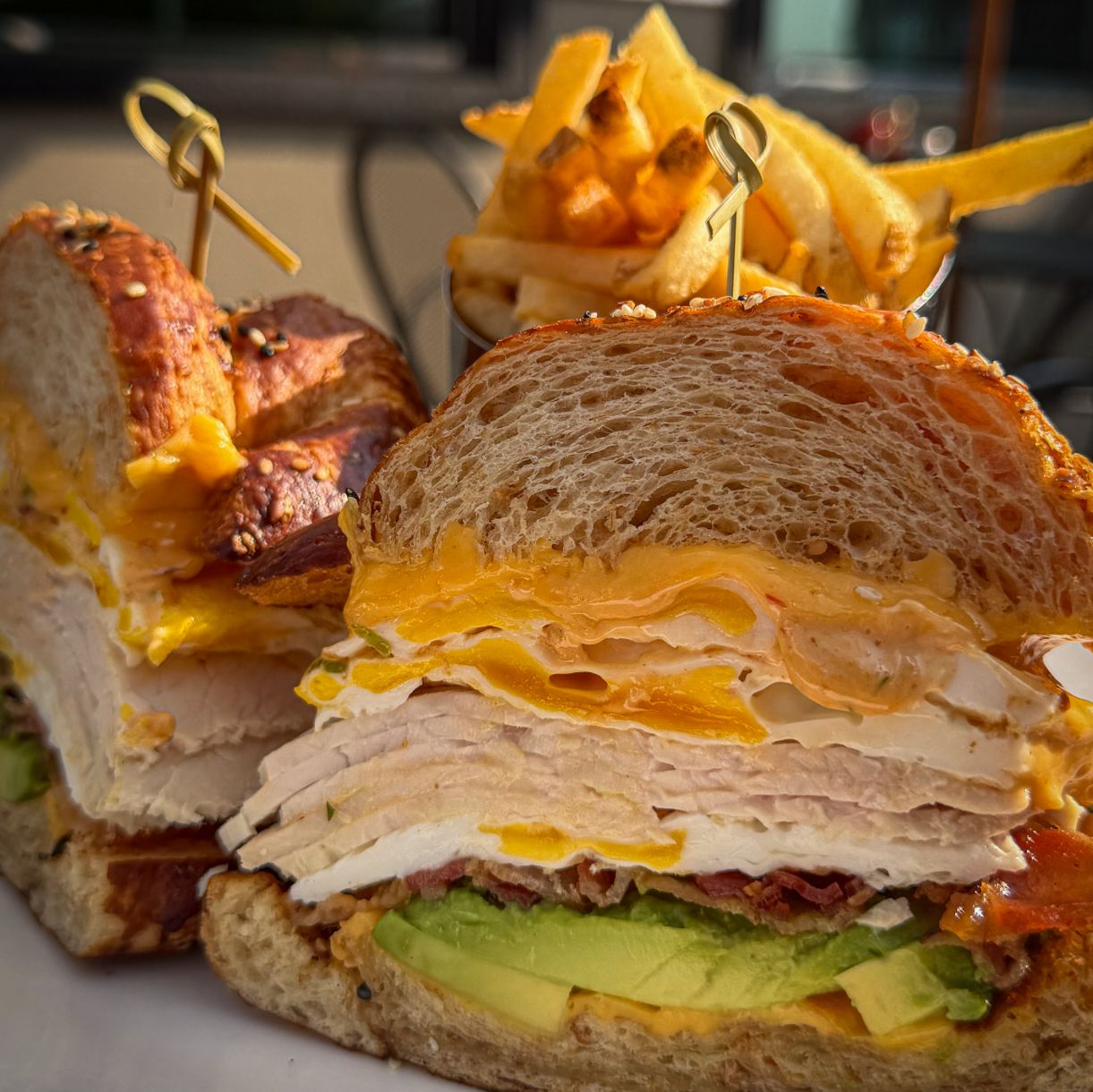 An egg sandwich on a pretzel croissant with avocado, turkey and bacon